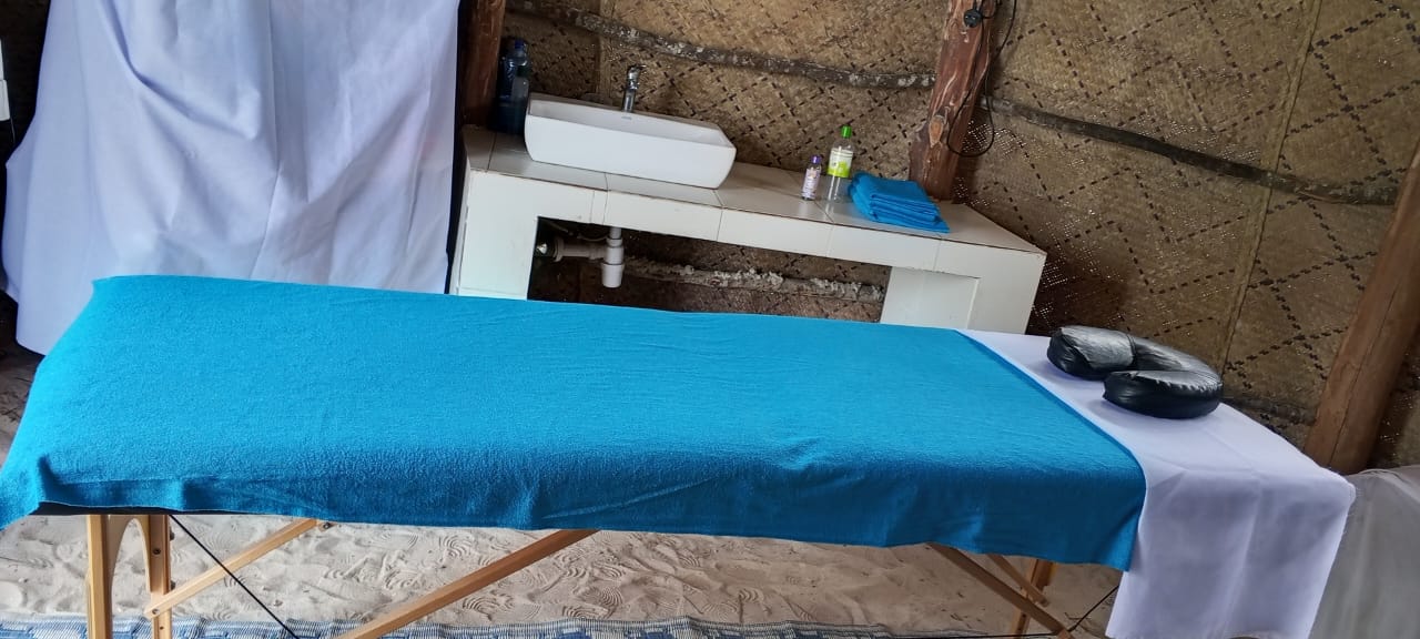 Treatment room with massage bed, sink and fresh towels