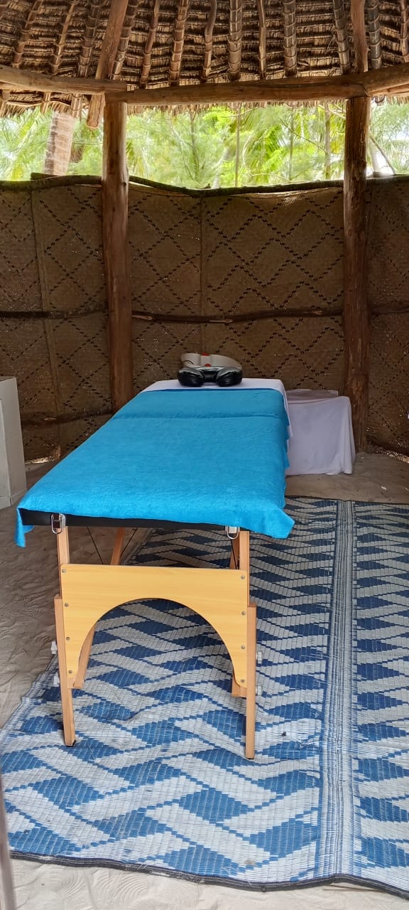 Thatched beach cabana with massage table on woven mat